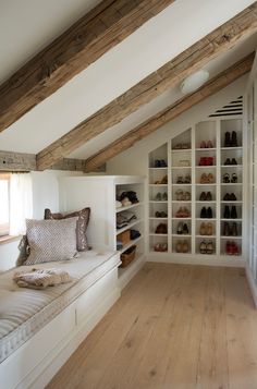 an attic bedroom with white walls and wooden flooring, built in shelving units