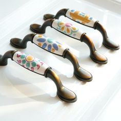 four decorative ceramic handles on a white surface