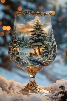 a wine glass sitting on top of snow covered ground with christmas lights in the background