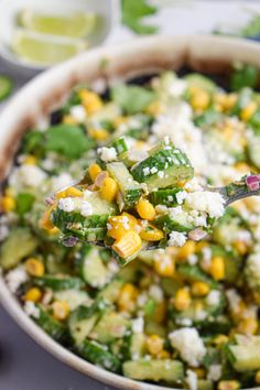 a close up of a spoonful of food with corn and feta on it