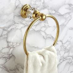 a gold towel holder on a marble countertop with a white cloth hanging from it