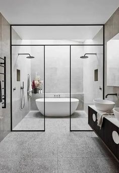 a modern bathroom with two sinks and a bathtub in the center, surrounded by glass walls