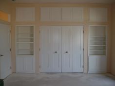 an empty room with white doors and shelves