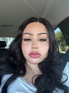 a woman with long black hair sitting in the back seat of a car and making a funny face