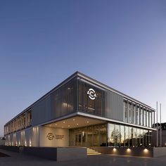 an office building that is lit up at night with lights on the front and side