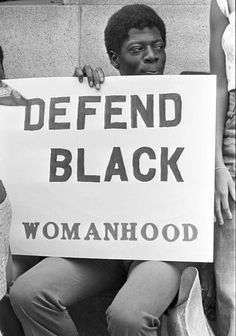 two people holding a sign that says defend black womanhood