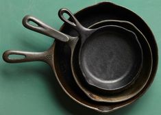 three cast iron skillets are stacked on top of each other, one is black and the other is brown