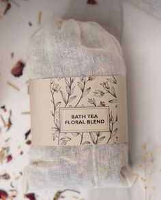 a bag of tea sitting on top of a white table next to dried flowers and leaves