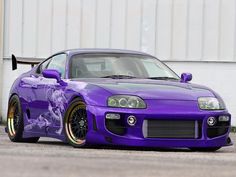 a purple sports car parked in front of a building