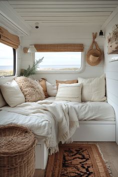 a white couch with pillows and blankets on top of it in front of a window