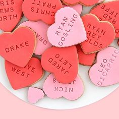 valentine's day cookies with names and hearts on a white plate against a pink background