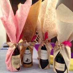 three wine bottles wrapped in paper and tied with pink ribbon are sitting on a table