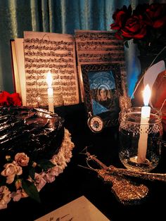 a table topped with pictures and candles on top of a black table covered in flowers