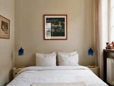 a white bed sitting under a window next to a radiator in a bedroom