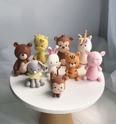 a group of small toy animals sitting on top of a white cake platter,