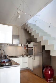 a modern kitchen with stainless steel appliances and stairs leading up to the upper floor area