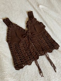 two brown crocheted bras laying on top of a bed