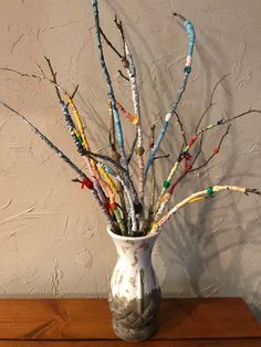 a vase filled with lots of branches on top of a wooden table next to a wall