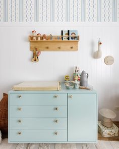 a baby's room with a dresser and toy shelf above the crib in blue