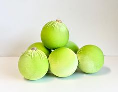 five lime green balls sitting on top of each other in front of a white background