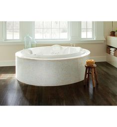 a large white bath tub sitting on top of a wooden floor next to a window