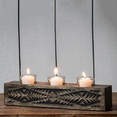 three lit candles are placed on a wooden block