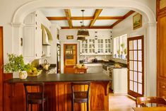 a kitchen with an island and wooden chairs in front of the counter top, along with white cabinets