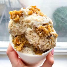 two scoops of ice cream in a white cup with crumbs on top