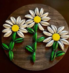 three white and yellow flowers sitting on top of a wooden board