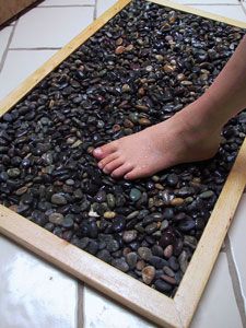 a person's bare foot is placed in a pile of rocks on the floor