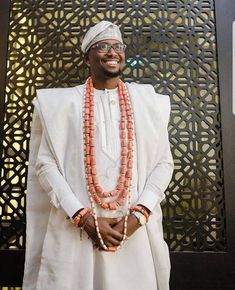 a man in a white suit and orange beads