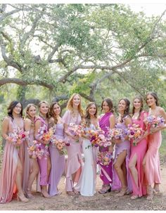 a group of women standing next to each other holding bouquets in their hands and wearing dresses