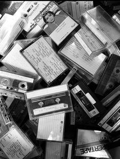 a pile of old and used cassettes are piled on top of each other in black and white