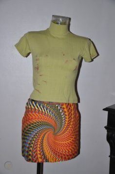 a mannequin wearing a yellow shirt and skirt with an orange spiral design on it