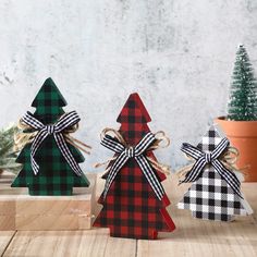 three wooden christmas trees with plaid bows on them