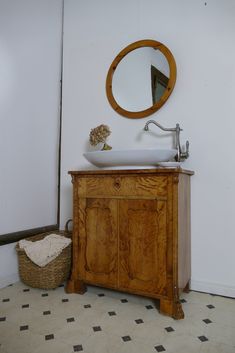 a bathroom sink sitting under a mirror next to a wooden cabinet with a bowl on it