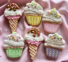 six decorated ice cream cones on a pink cloth