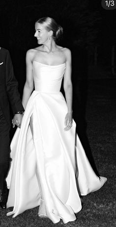 black and white photo of bride and groom holding hands in the grass at their wedding