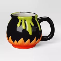 a black and orange coffee mug with green drips