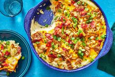 a casserole dish with meat, cheese and vegetables on it next to two plates