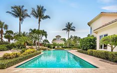 a pool surrounded by trees and bushes next to a house