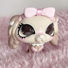 a close up of a small toy on a pink blanket with big eyes and large eyelashes