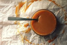 a glass filled with liquid sitting on top of a piece of wax paper next to a spoon