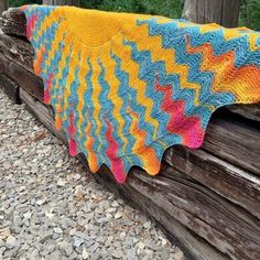 there is a colorful crocheted blanket on top of a log