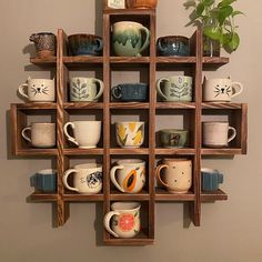 a wooden shelf filled with lots of coffee mugs and cups on top of it