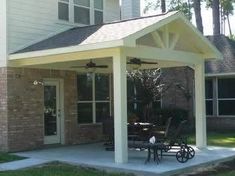 a covered patio with tables and chairs in front of a house on a sunny day