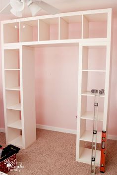 a room with pink walls and a white book shelf in the corner, next to a ladder