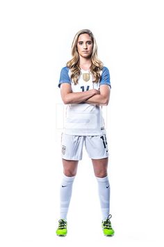 a female soccer player is posing for a photo with her arms crossed and looking at the camera