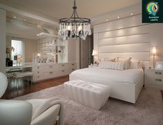 a large white bed sitting in a bedroom under a chandelier