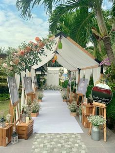 an outdoor ceremony setup with white linen and flowers on the aisle, surrounded by greenery